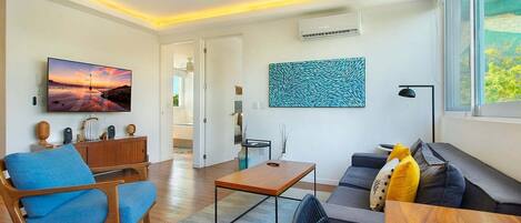Un salon moderne avec un téléviseur à écran plat, une table basse, un canapé et une table à manger.