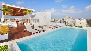 Un espace piscine sur le toit, avec des chaises longues et un coin salon abrité.