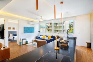 Eine moderne Küche mit einer zentralen Kochinsel, ein Essbereich mit einer Couch und Blick auf ein Wohngebäude.