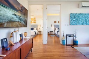 A modern living room with a wooden floor, a large painting, and a blue abstract artwork. - 2BR Downtown Condo Walk to Coco Beach (Playa Del Carmen)