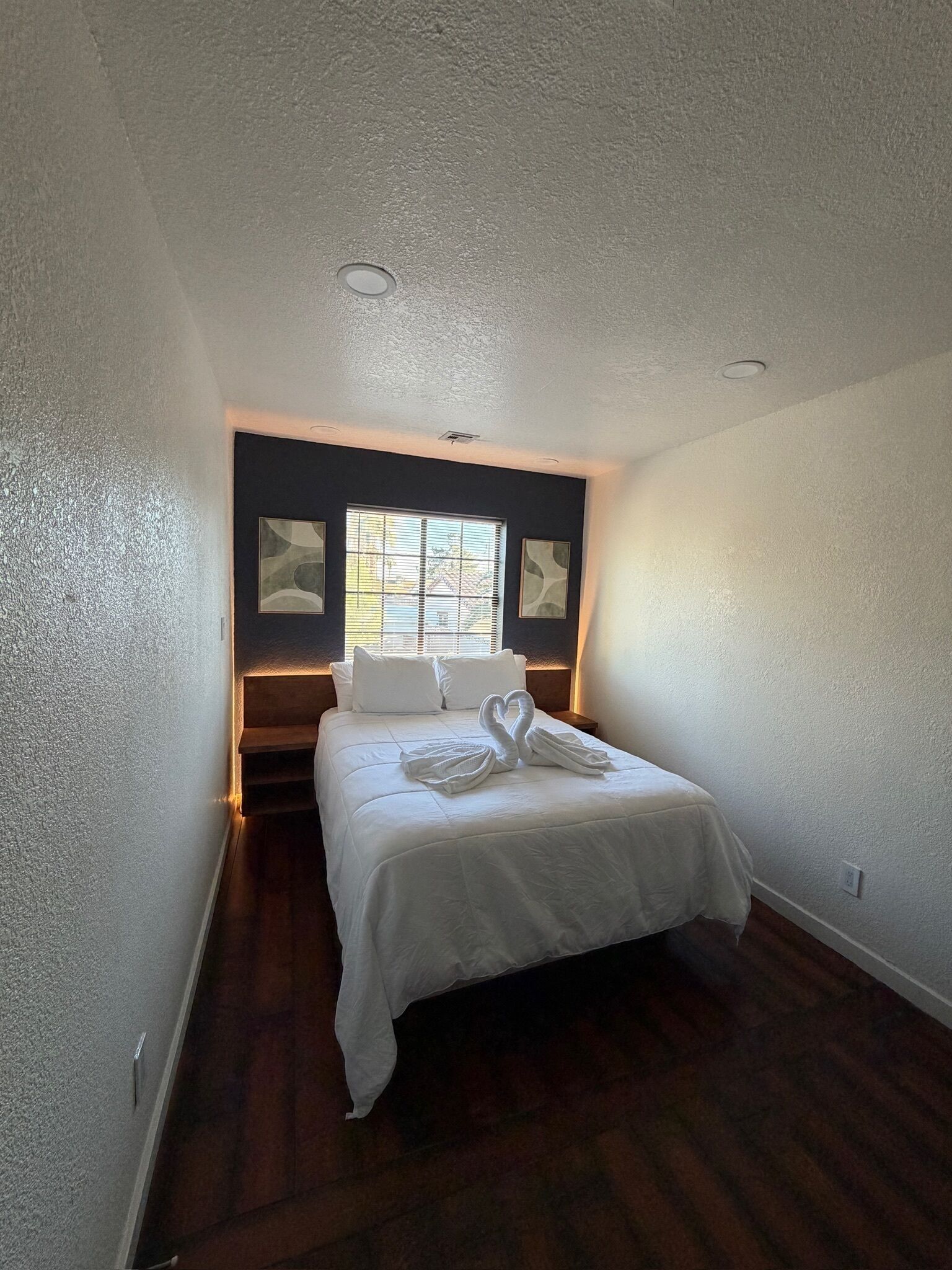 A bedroom with a bed, a window, and artwork on the walls.
