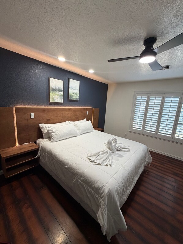 A hotel room with a bed, a nightstand, a ceiling fan, and a window with blinds. - 5-Bedroom Luxury Home | Jacuzzi/Sauna/BBQ | 15 Min from the Strip (Las Vegas)