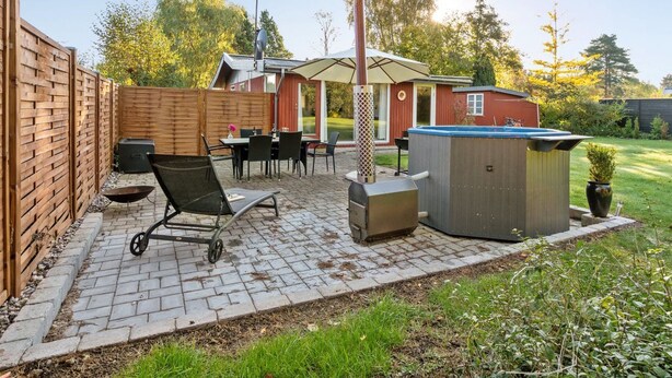 Un patio trasero con una parrilla, mobiliario exterior y un jacuzzi.