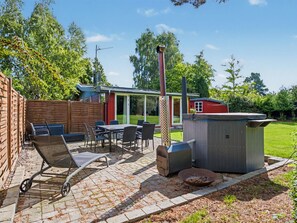 Eine Terrassengruppe im Freien mit Grill, Sitzgelegenheiten und einem Holzzaun.