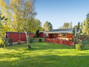 Il s’agit d’une propriété résidentielle comprenant un bâtiment rouge, une cour clôturée et un arbre.