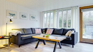 Una sala de estar moderna con un sofá seccional gris, una mesa de centro de madera y una lámpara de pie.
