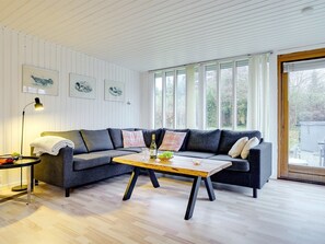 Ein modernes Wohnzimmer mit einem grauen Ecksofa, einem Holztisch und einer Stehlampe.