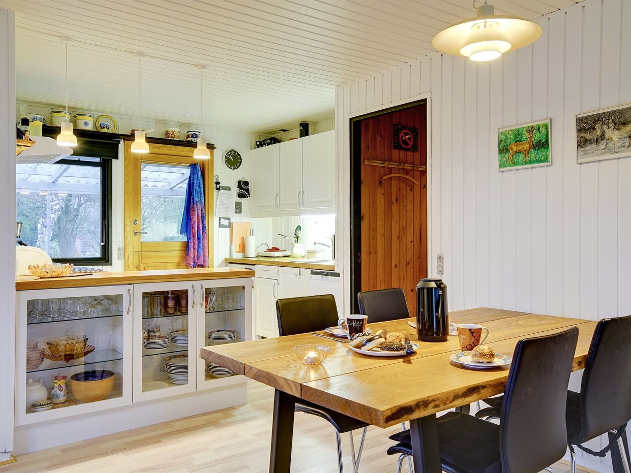 A cozy kitchen with wooden cabinets, a dining table with chairs, and a coffee machine.