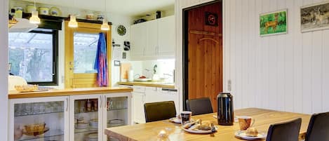A cozy kitchen with wooden cabinets, a dining table with chairs, and a coffee machine.