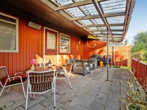 A covered patio area with a table and chairs, a grill, and a wooden fence. - "Aasta" - 500m from the sea by Interhome (Præstø)