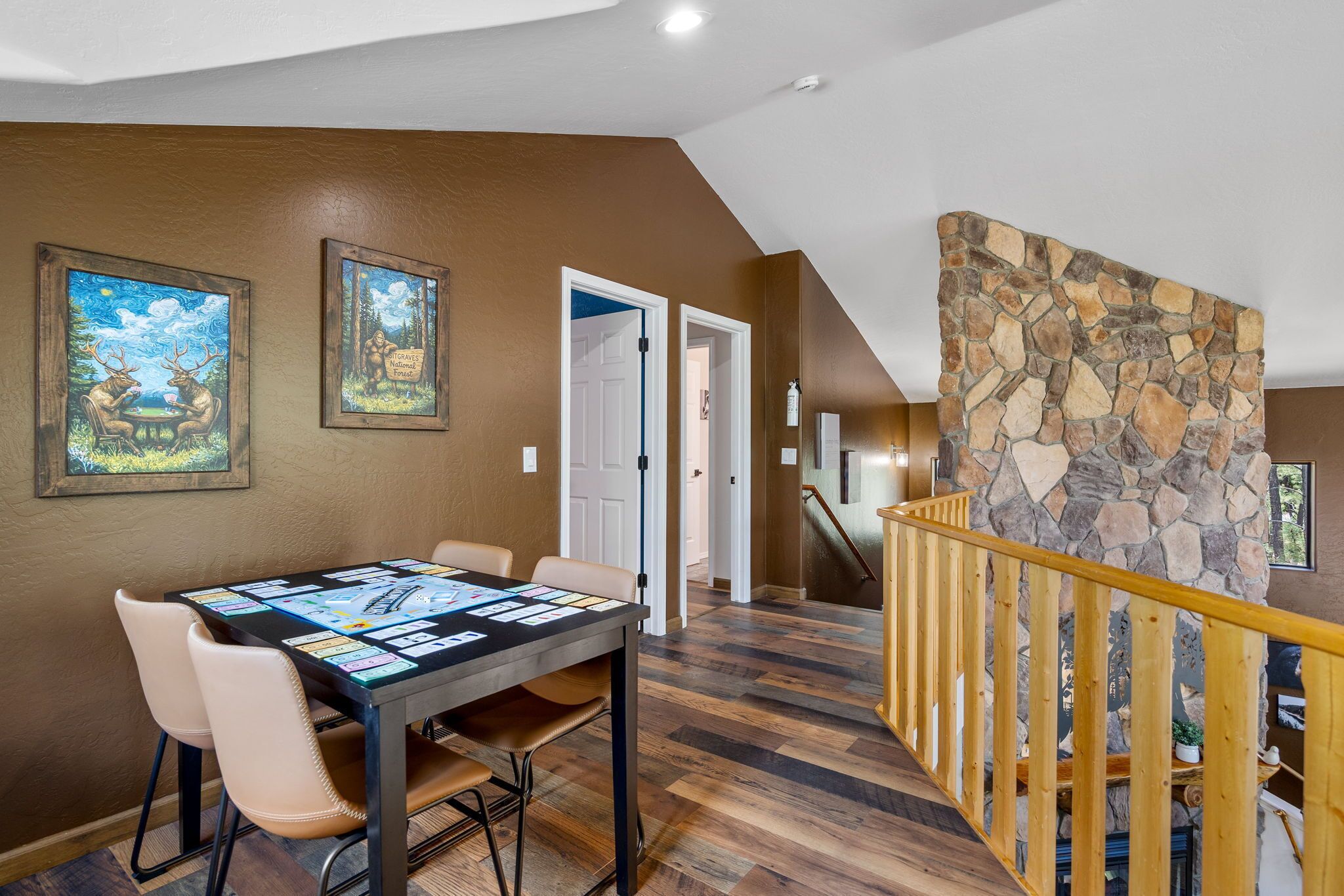 A dining area with a table set for four, a staircase with a wooden railing, and a stone wall.