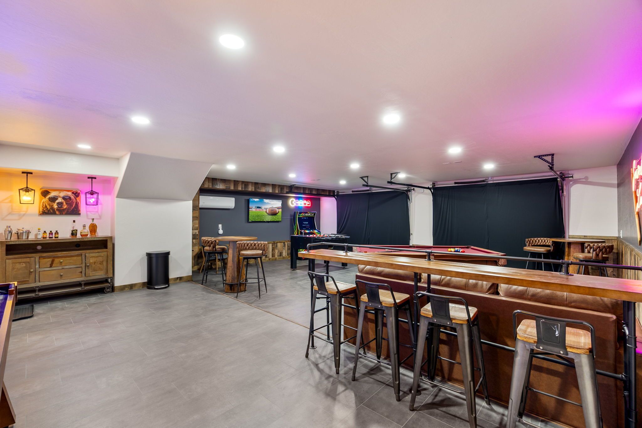 A bar area with stools, a pool table, and a foosball table.
