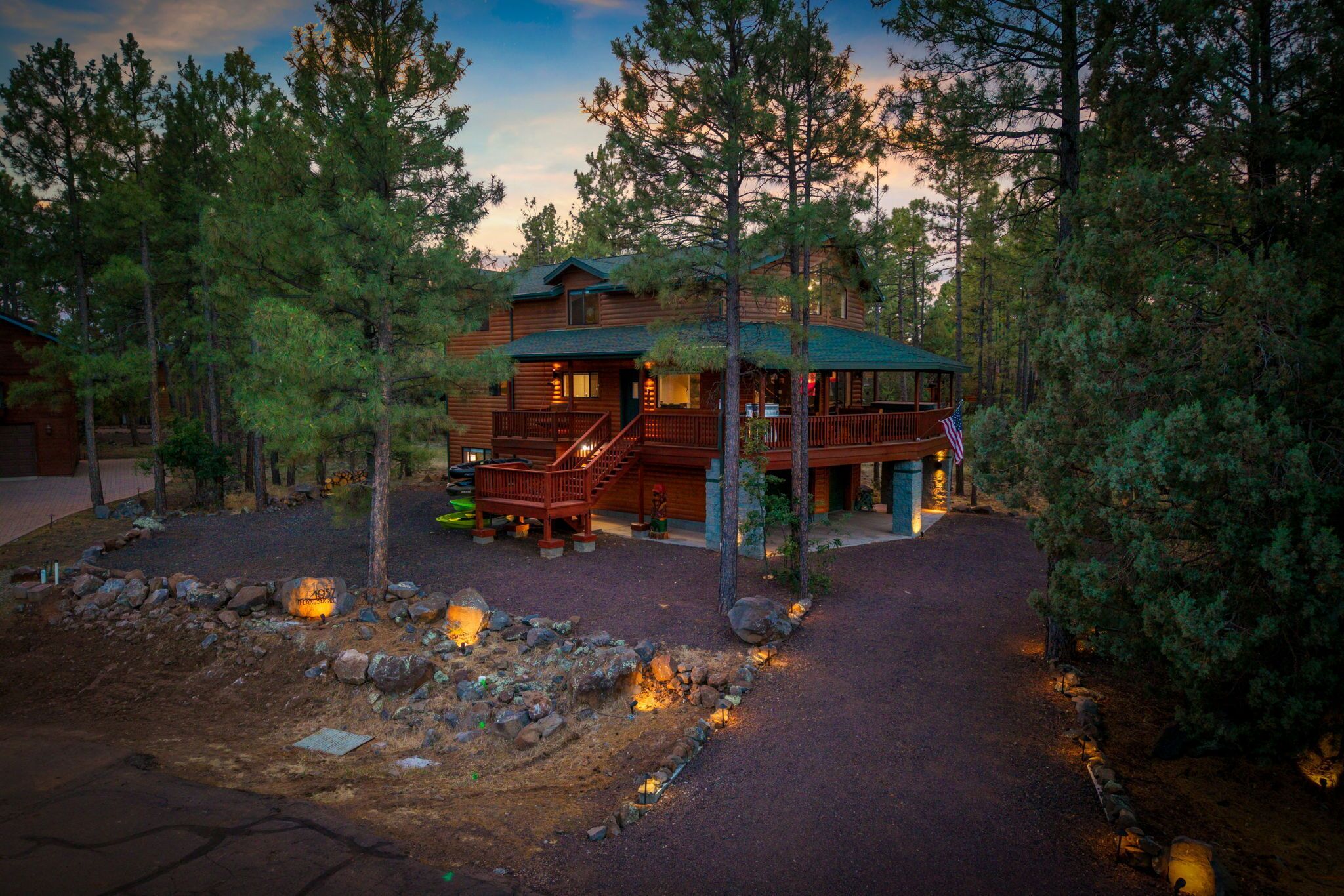 A two-story log cabin with a covered porch and a stone foundation.