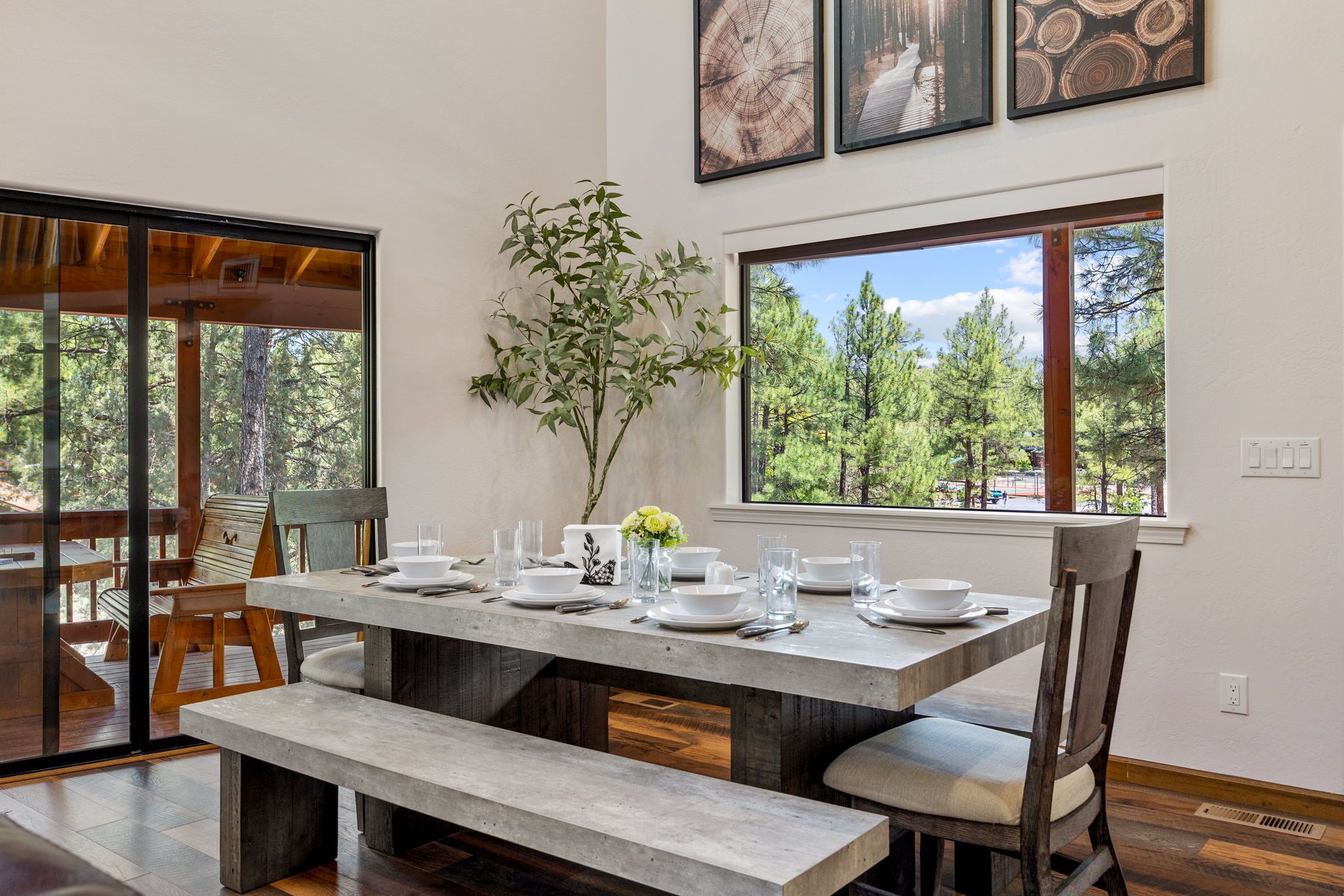 A dining area with a wooden table set for four, benches, and a vase with flowers.