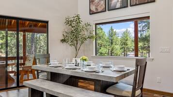 A dining area with a wooden table set for four, benches, and a vase with flowers.