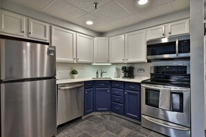 A modern kitchen with stainless steel appliances, white cabinets, and a blue accent wall. - Treetop Hearth at Mountain Green | 1BR Balcony Condo | Sleeps 4 (Killington)