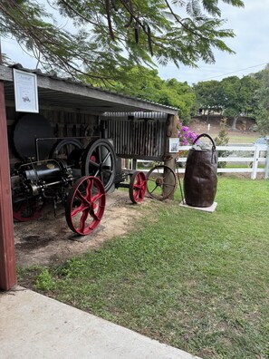 A vintage steam engine with red wheels, a large black tank, and a wooden structure with a sign.