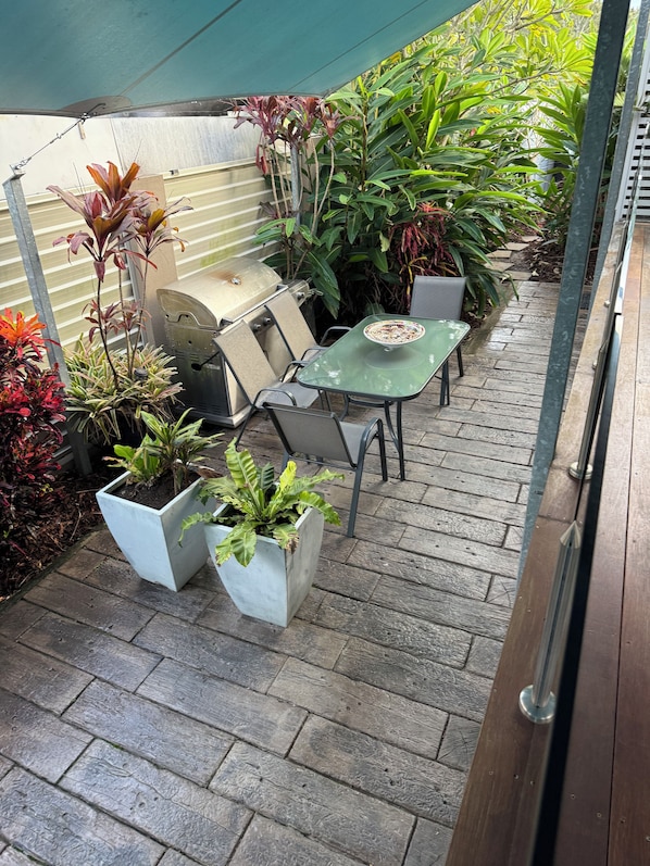 A patio area with a grill, outdoor seating, and potted plants.