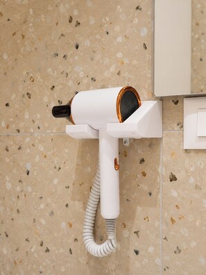 A hair dryer mounted on a wall with a speckled tile background. - R&RS STUDIO APART (Golem)