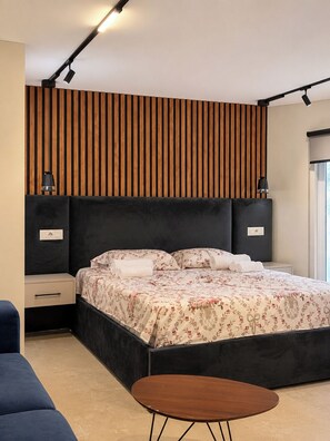 Una camera da letto moderna con un letto grande, un comodino, un tavolino e un lampadario a parete.