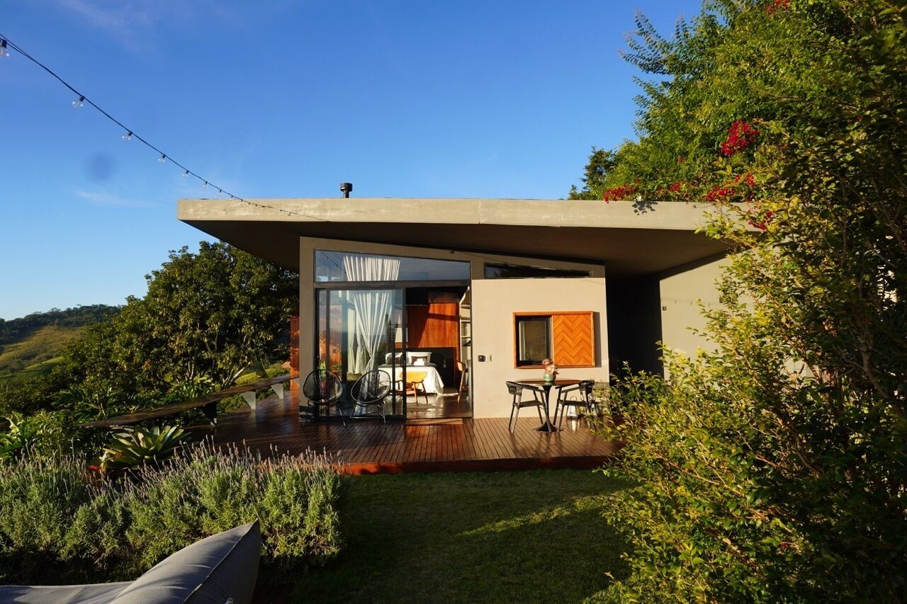Uma casa moderna com entrada por porta de vidro, um pátio com móveis de exterior e vista para a paisagem ao redor.