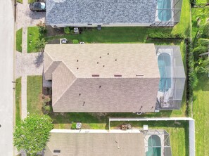 An aerial view of a residential area with a house featuring a sloped roof, a swimming pool, and a well-maintained lawn. - Charming 4-bedroom house with AC in welcoming Davenport (Davenport)