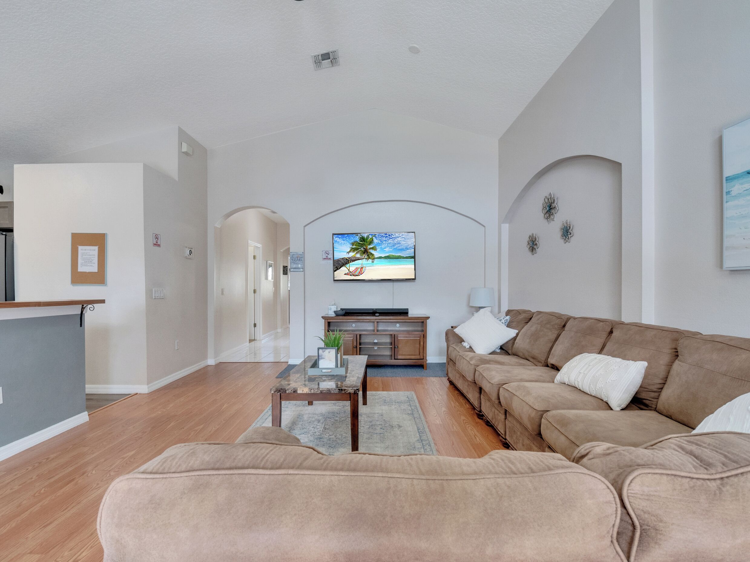 A modern living room with a sofa, coffee table, and a flat-screen TV mounted on the wall.