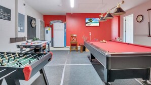 Uma sala de lazer com mesa de futebol de mesa, mesa de bilhar e dardos.