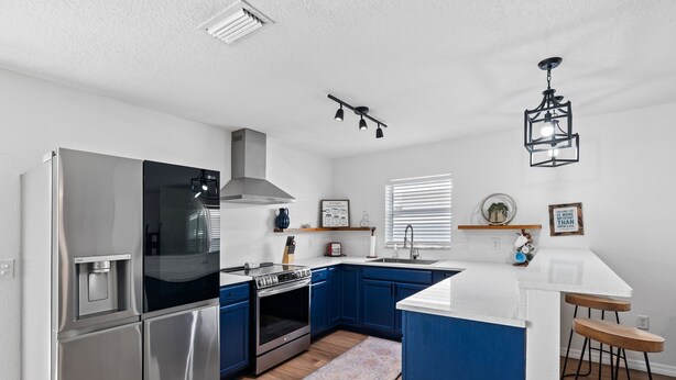 Een moderne keuken met roestvrijstalen apparatuur, blauwe keukenkastjes en een centraal eiland.
