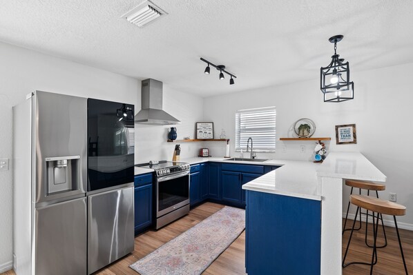 A modern kitchen with stainless steel appliances, blue cabinets, and a central island. - Discover the Best of Central Florida from Wimauma (Wimauma)