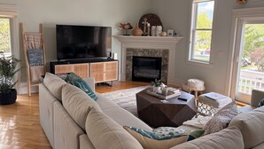 Ein Wohnzimmer mit einer Couch, einem Fernseher, einem Kamin und einem Fenster mit Blick.
