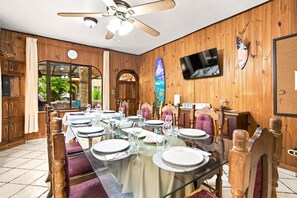 A dining area with a glass table, wooden chairs, and a ceiling fan. - 11 beds, 9 bdrm, 6 bath - Short walk to Bars, Cocal Casino & Beach (Jacó)