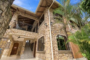 Ein zweistöckiges Steinhaus mit Balkon, Treppe und Eingangstür.