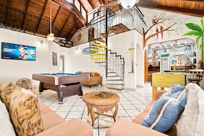 A spacious living area with a pool table, comfortable seating, a staircase with a unique design, and a bar area with various bottles. - 11 beds, 9 bdrm, 6 bath - Short walk to Bars, Cocal Casino & Beach (Jacó)