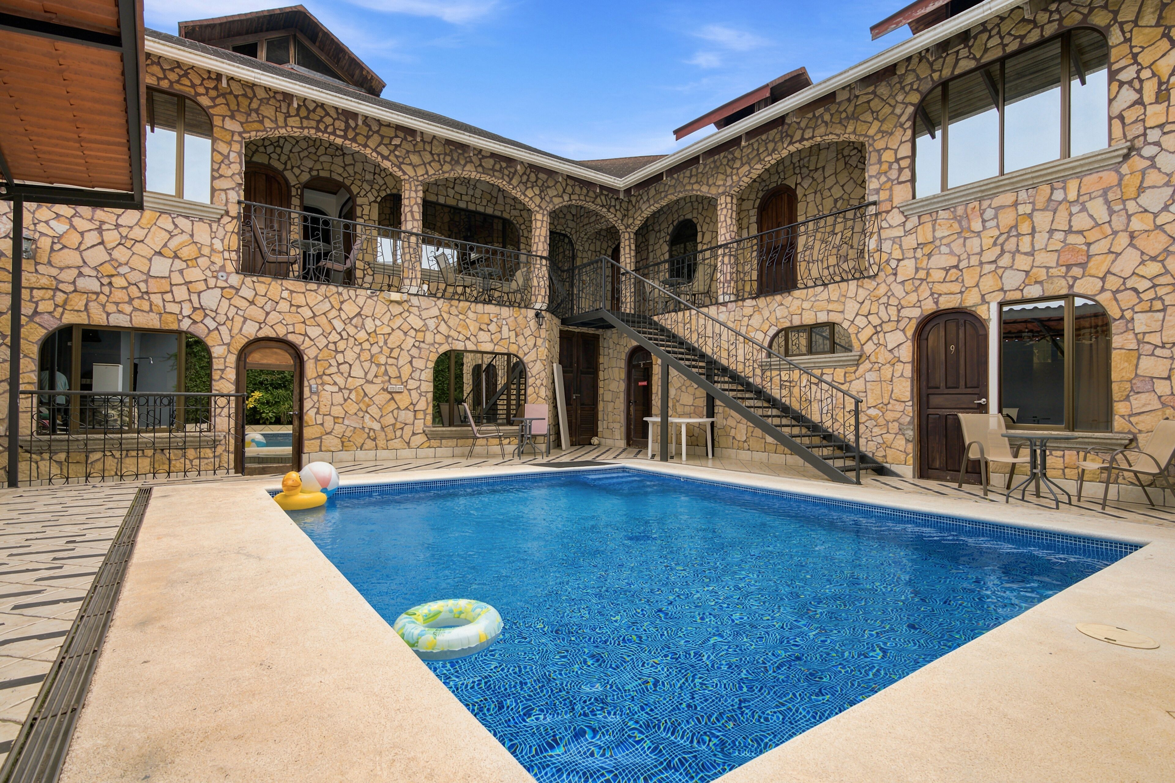 A pool area with a stone building, a staircase, and outdoor seating.
