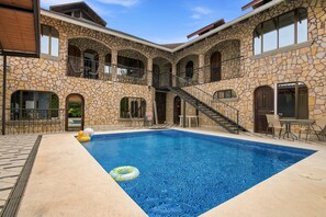 A pool area with a stone building, a staircase, and outdoor seating. - 11 beds, 9 bdrm, 6 bath - Short walk to Bars, Cocal Casino & Beach (Jacó)