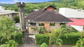 A castle-like structure with a stone tower, a red-roofed building, and lush greenery. - 11 beds, 9 bdrm, 6 bath - Short walk to Bars, Cocal Casino & Beach (Jacó)
