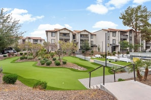 A residential building with a landscaped garden and a golf putting area. - Stylish 2BR Getaway Near ASU | Pools, Gym + Parking (Tempe)