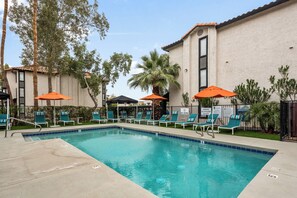 A pool area with lounge chairs and umbrellas, surrounded by a building with a tiled roof and palm trees. - Stylish 2BR Getaway Near ASU Pool, Gym + Parking (Tempe)