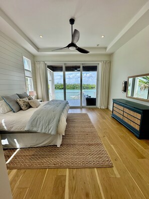 A bedroom with a bed, a ceiling fan, a large window, and a view of the outdoors. - Waterfront 7-bedroom house in Bonita Springs with its own Pickleball court (Bonita Springs)