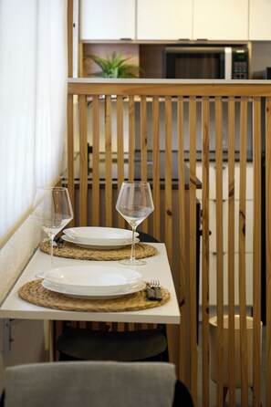 A dining area with a wooden partition, two wine glasses, white plates, and a woven placemat. - Modern studio apartment for 2 in Pocitos, just steps from the Rambla (Montevideo)