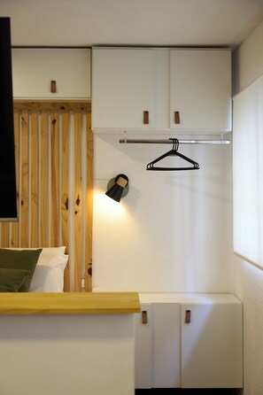A bedroom with a bed, a bedside table, a hanging light, and a wardrobe. - Modern studio apartment for 2 in Pocitos, just steps from the Rambla (Montevideo)