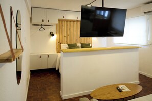 A compact living space with a flat-screen TV mounted on the wall, a small wooden table, and a sofa with cushions. - Modern studio apartment for 2 in Pocitos, just steps from the Rambla (Montevideo)