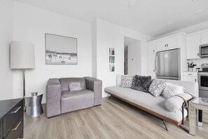 A modern living room with a grey sofa, a flat-screen TV, and a minimalist design. - Slabtown TC Condo | Pets Welcome + Near Dog Park (Traverse City)