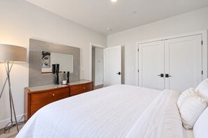 A bedroom with a large bed, a dresser, a mirror, and a wardrobe. - Slabtown TC Condo | Pets Welcome + Near Dog Park (Traverse City)
