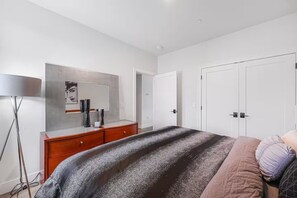 Une chambre à coucher comprenant un lit, une commode, un miroir et une armoire.