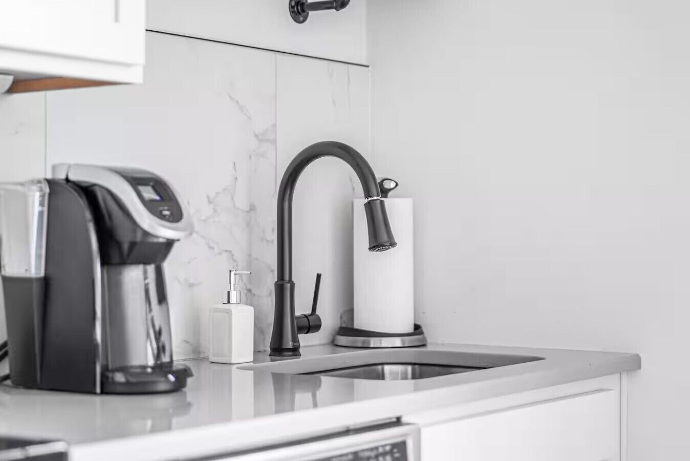 Eine moderne Küche mit integrierter Kaffeemaschine, einem Wasserhahn und einer Seifenspender.