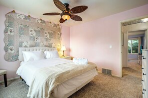 Ein Schlafzimmer mit einem großen Bett, einem Deckenventilator, einer Wandteppich und einem Nachttisch mit Lampe.