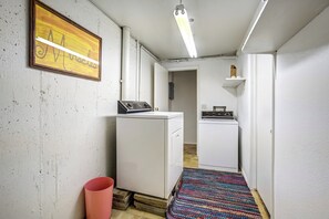 A laundry room with two washing machines, a dryer, a colorful woven rug, and a framed artwork on the wall. - The Broadmoor Condo | 2 Queens + Garage (Colorado Springs)