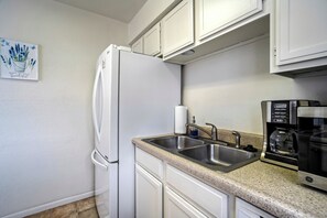 A kitchen with white cabinets, a stainless steel sink, a coffee maker, and a refrigerator. - The Broadmoor Condo | 2 Queens + Garage (Colorado Springs)